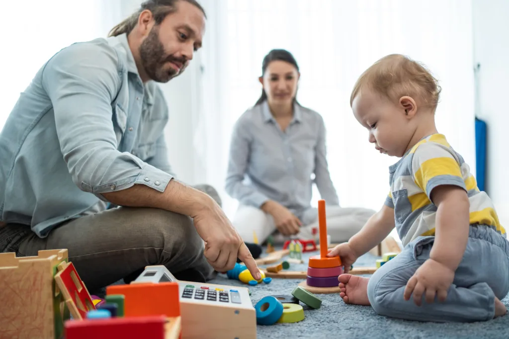 Child playing with educational toys while a caregiver guides learning in a nurturing child care center environment.