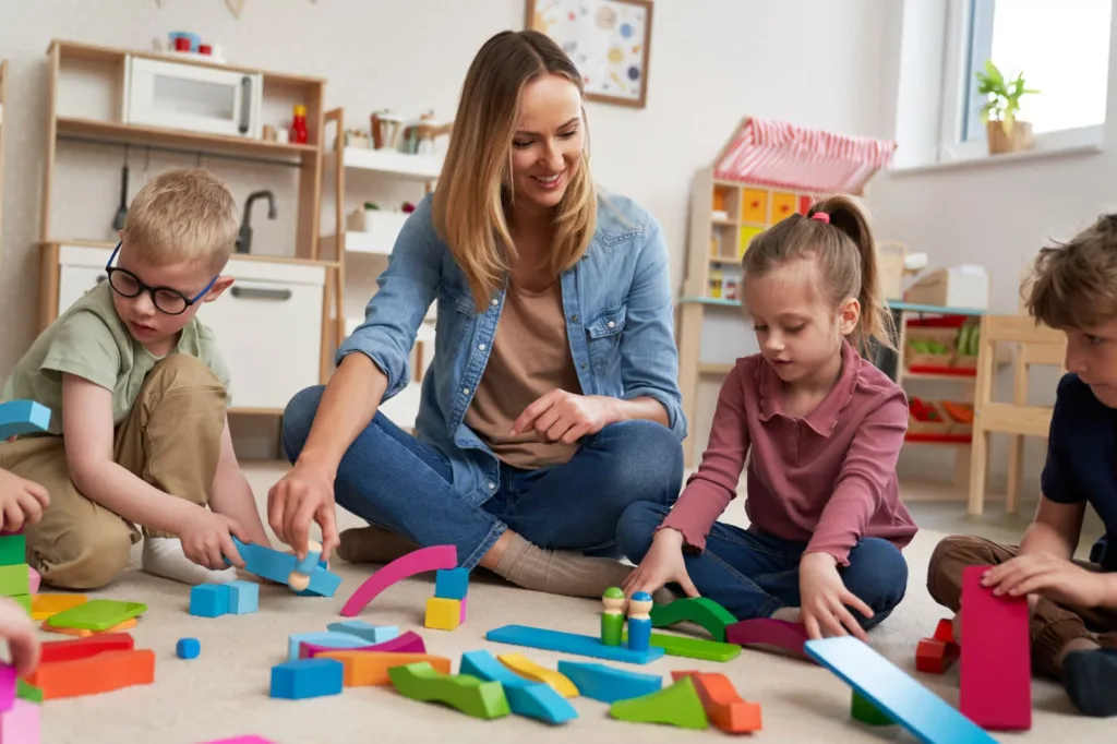 A bright, spacious, and modern child care center interior designed with high-quality wooden play structures, sorting zones, and inclusive play areas for toddlers.