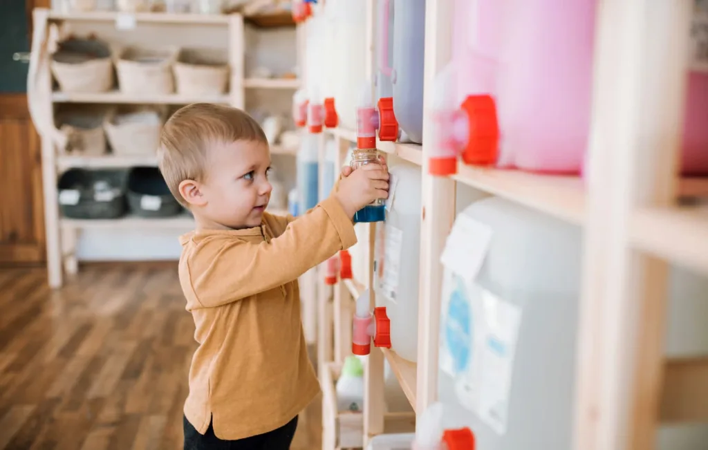A caring early childhood educator guiding two young toddlers through a cooperative block-building activity inside a warm, supportive surrey bc daycare classroom environment.